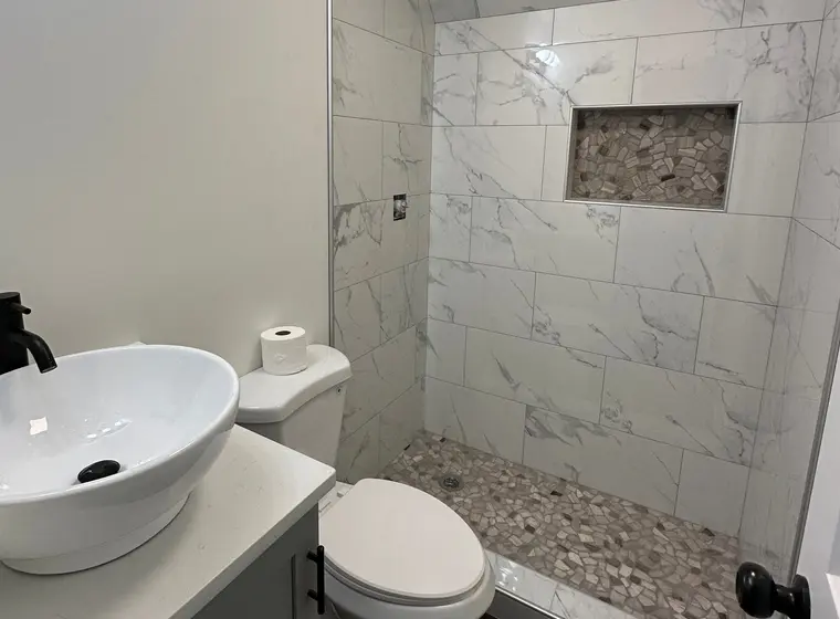 Guest bath with marble shower, pebble niche and vessel sink