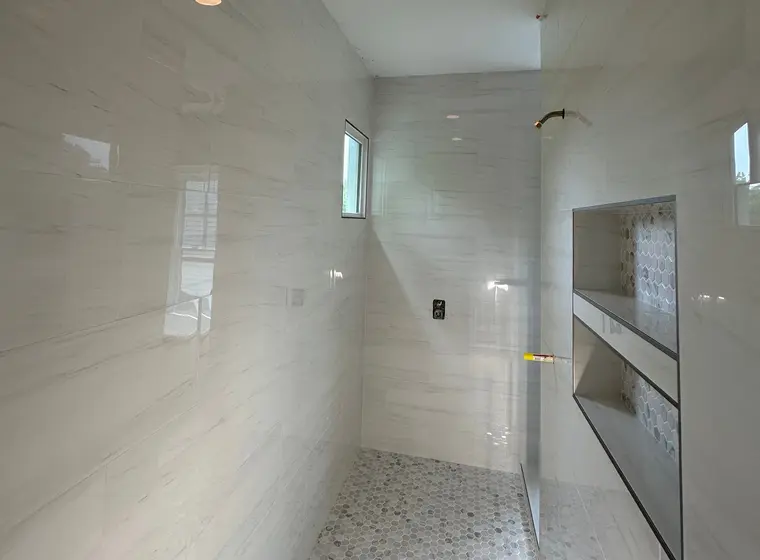 Large-format marble-look porcelain across floor and shower walls