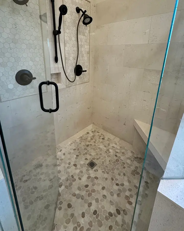 Limestone shower with pebble floor and hex mosaic bench, set by B & B Pro Tile