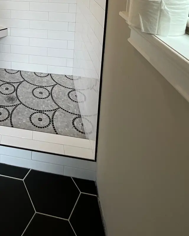 Custom circle-mosaic shower floor framed by black hexagon tile