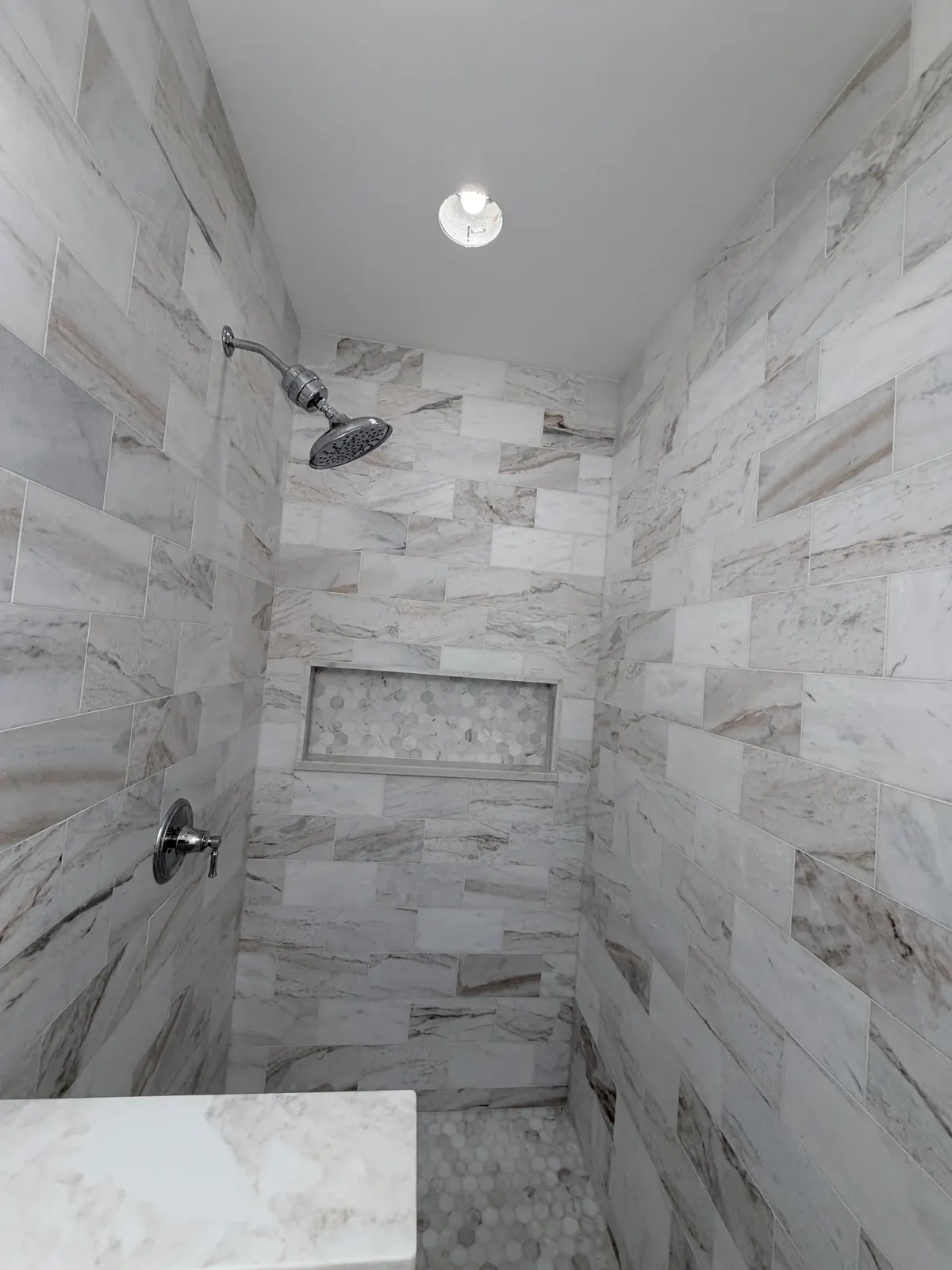 Marble-strip shower with mosaic niche, materials chosen with the client